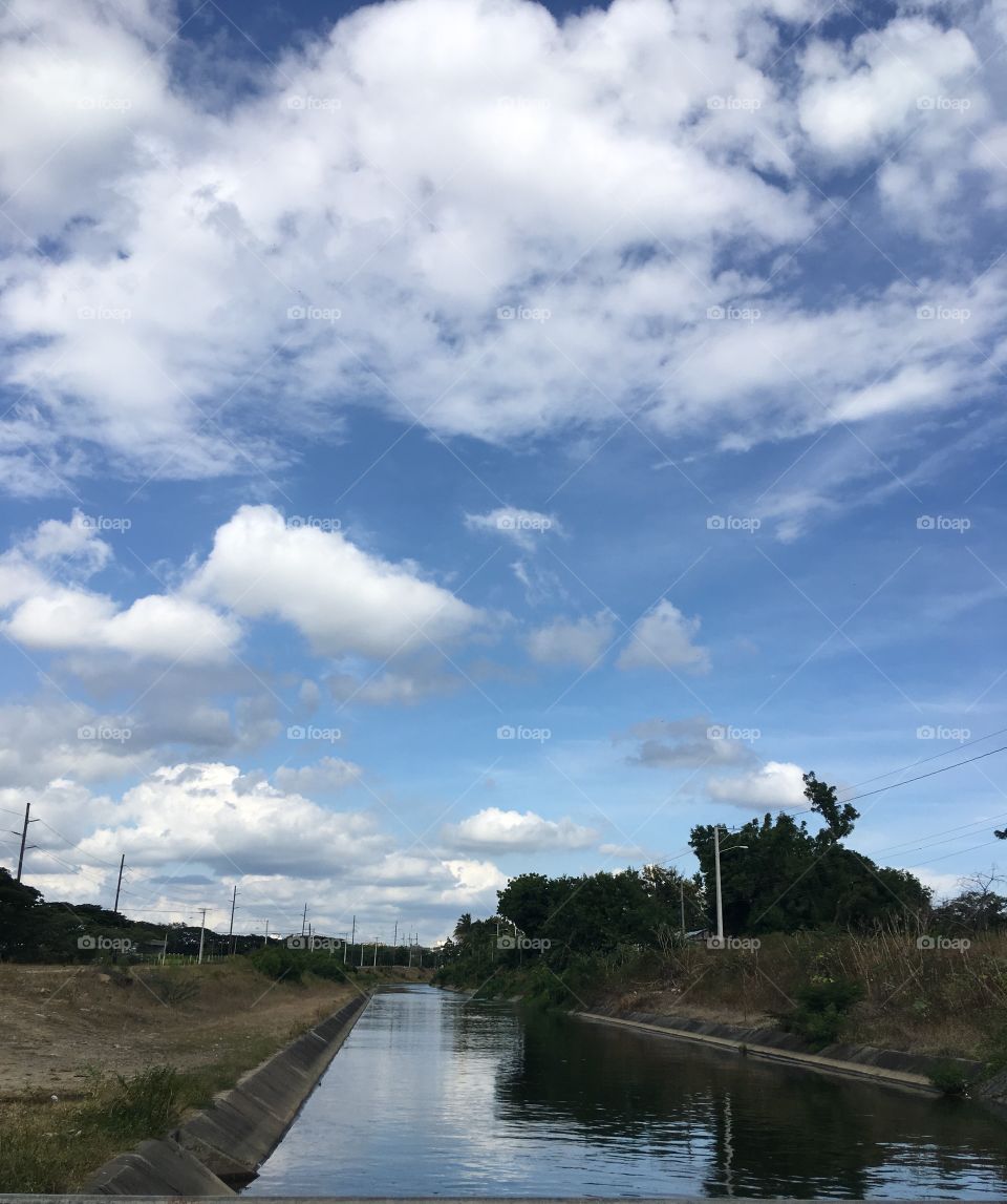 Canal de agua con un hermoso cielo azulado con pequeñas nubes