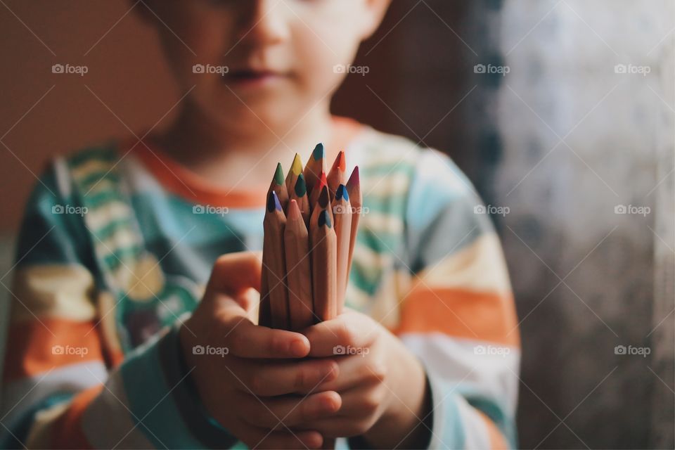 Close-up of hand holding colorful pencils 