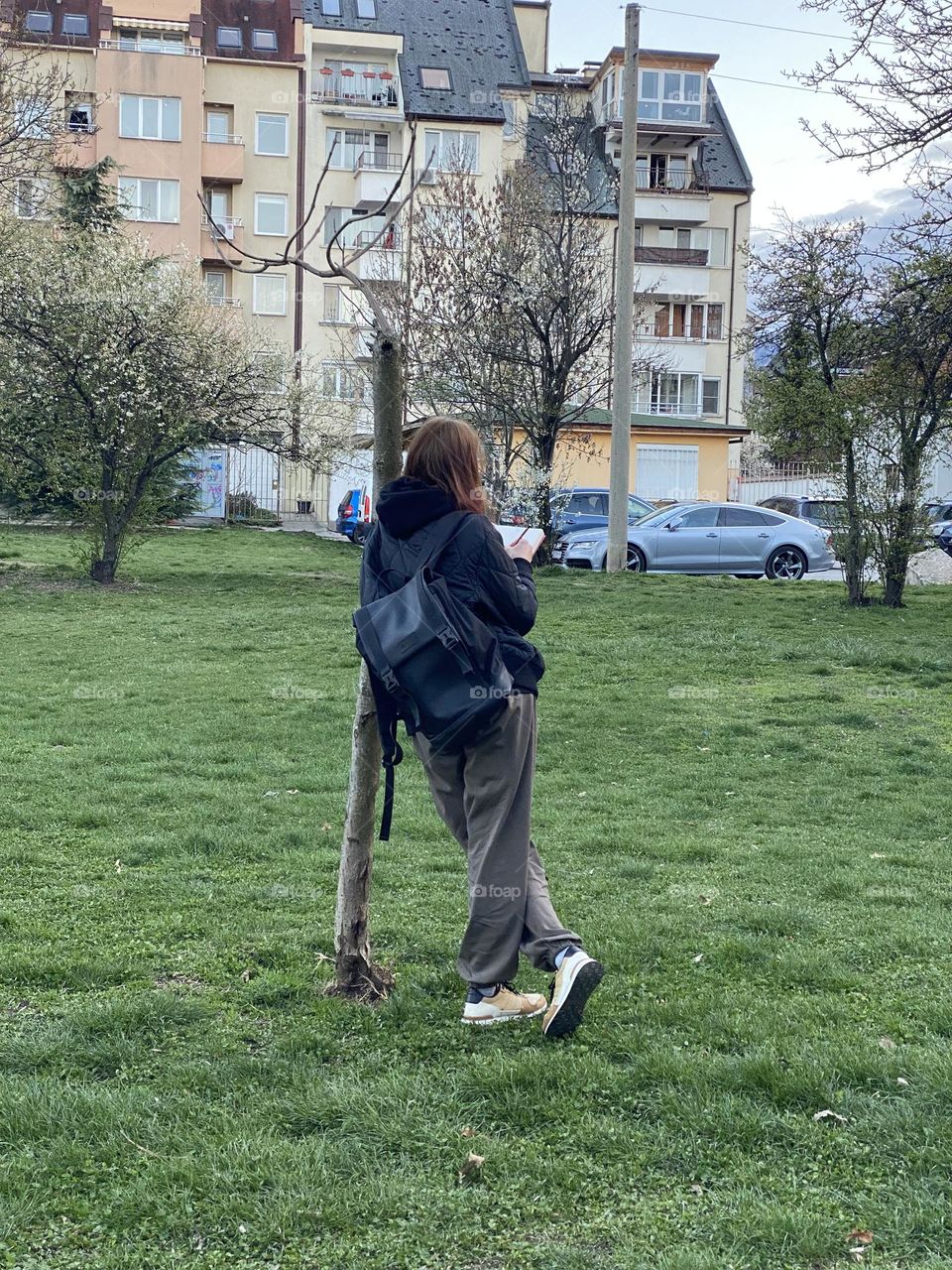 A girl paints a blossoming spring tree in the park