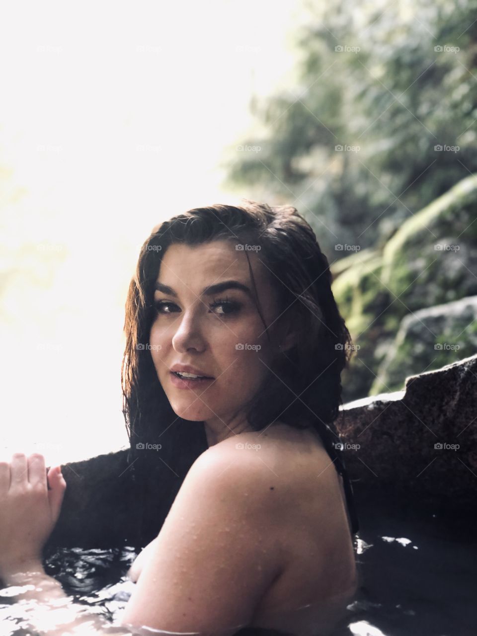 Girl swimming in beautiful Idaho hot spring in the middle of winter. 