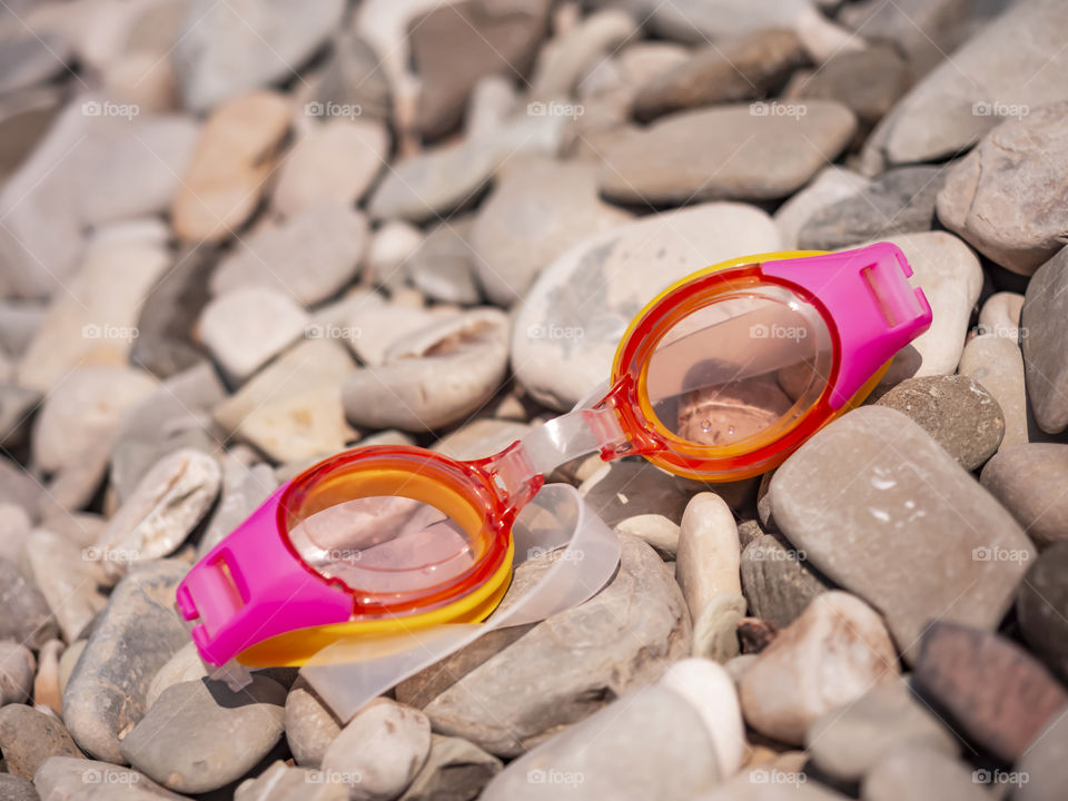 Goggles for swimming and diving lie on the rocky beach of the southern coast of the sea
