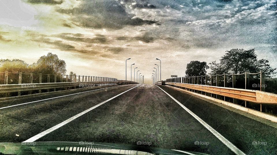 Straight road against dramatic sky