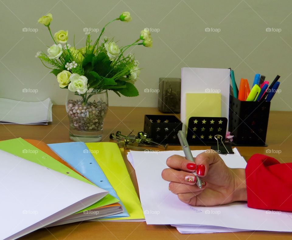  working on the writing table , there is pen , book, pencil , stapler , clip, read , papers, a lot of work ...hand woman 