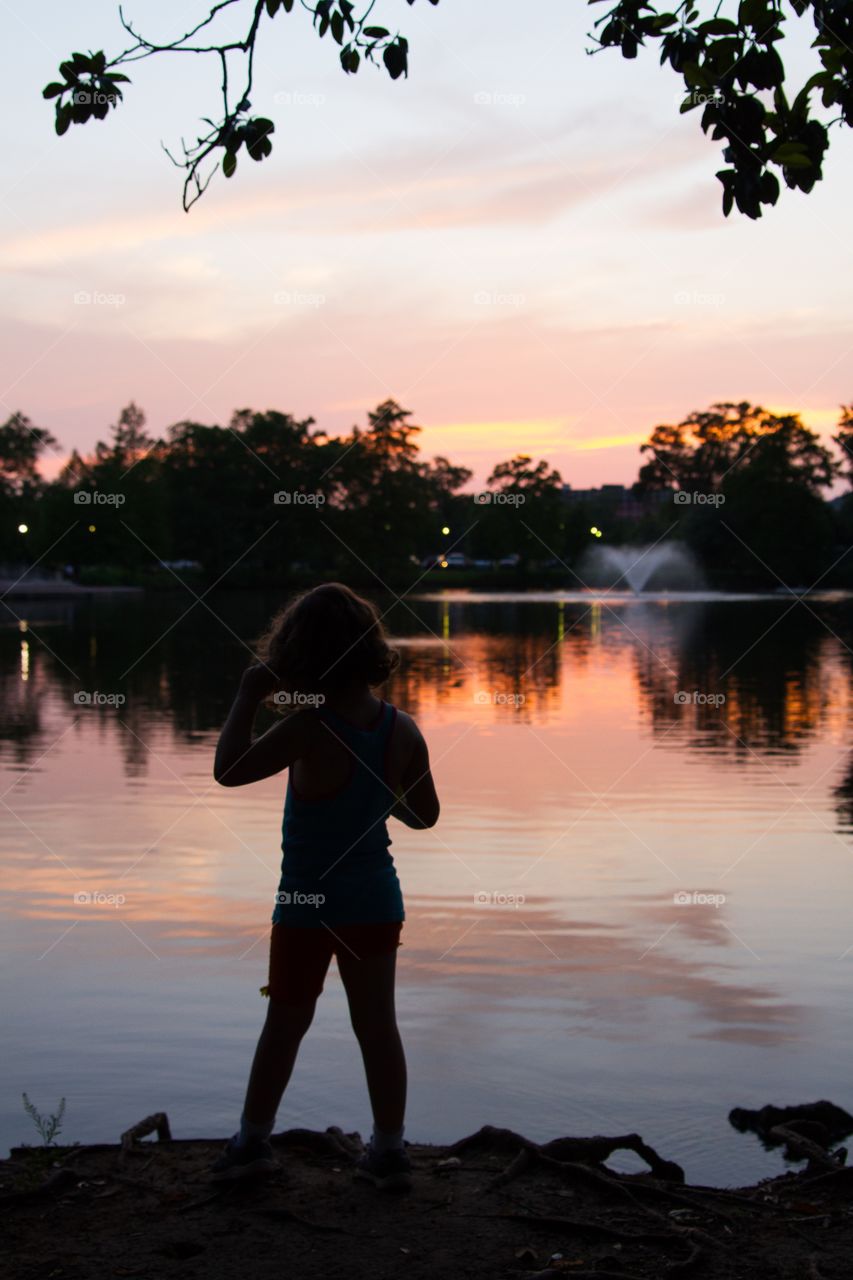 Girl at lake during sunset with colorful dusk sky
