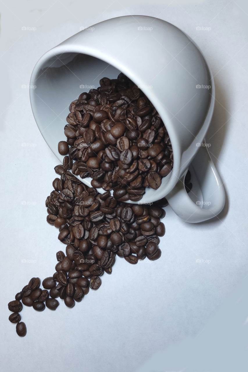 White cup with roasted coffee beans