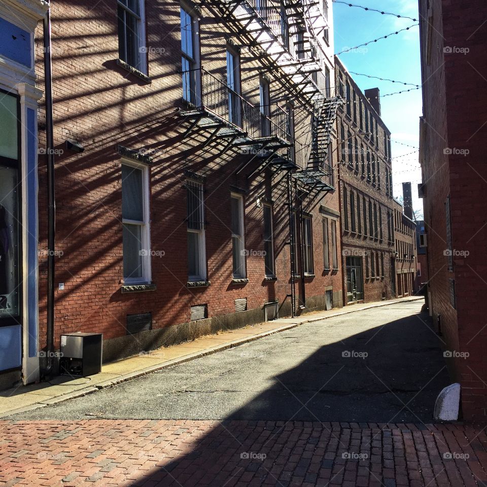 An alley in Salem, Massachusetts includes brickwork, ironwork, and long shadows.