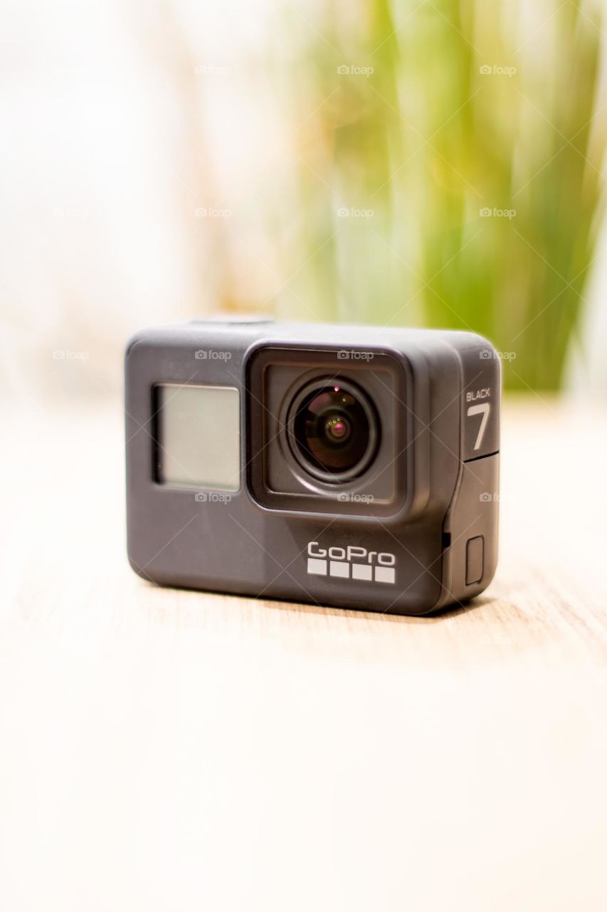 A GoPro action camera sitting on a modern wooden table in bright scene