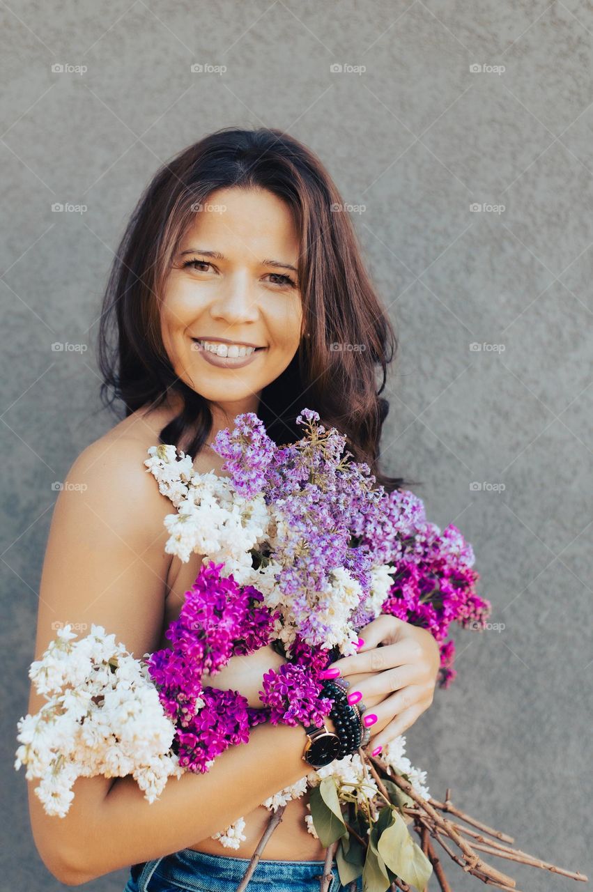 portrait of a beautiful woman brunette holding blue and purple lilac flowers