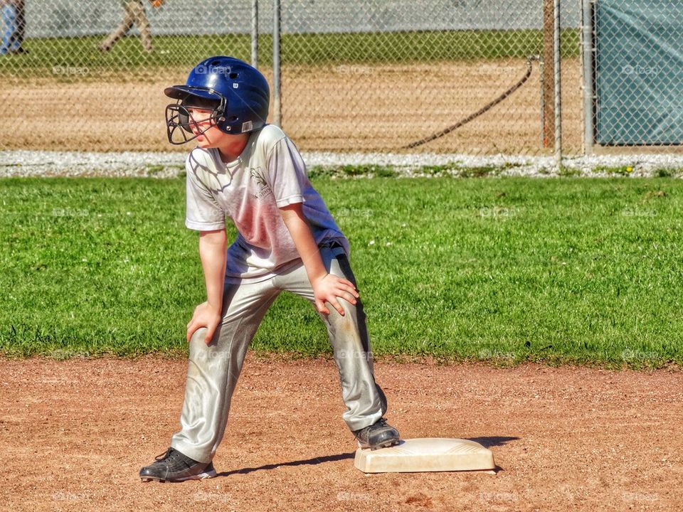 Young Baseball Player Leading Off Base. Young Baseball Player Getting Ready To Run
