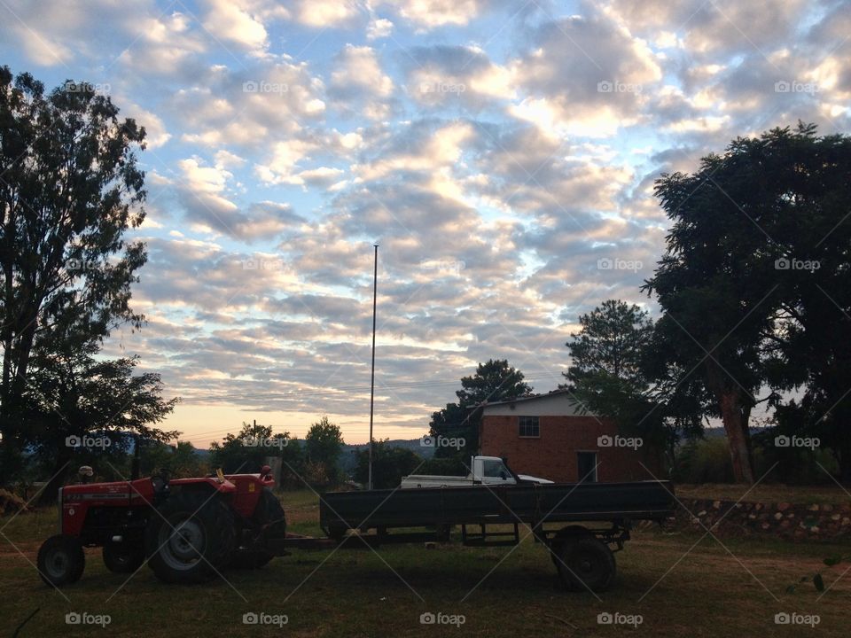 Clouds scatter the light as a backdrop to farm equipment