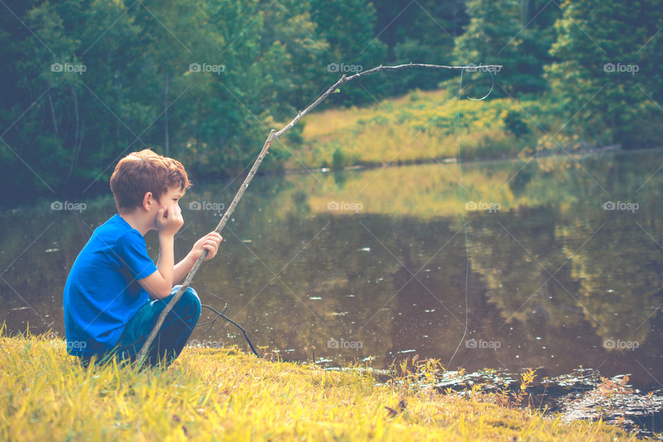 Young Boy Fishing in a Pond with Homemade Pole