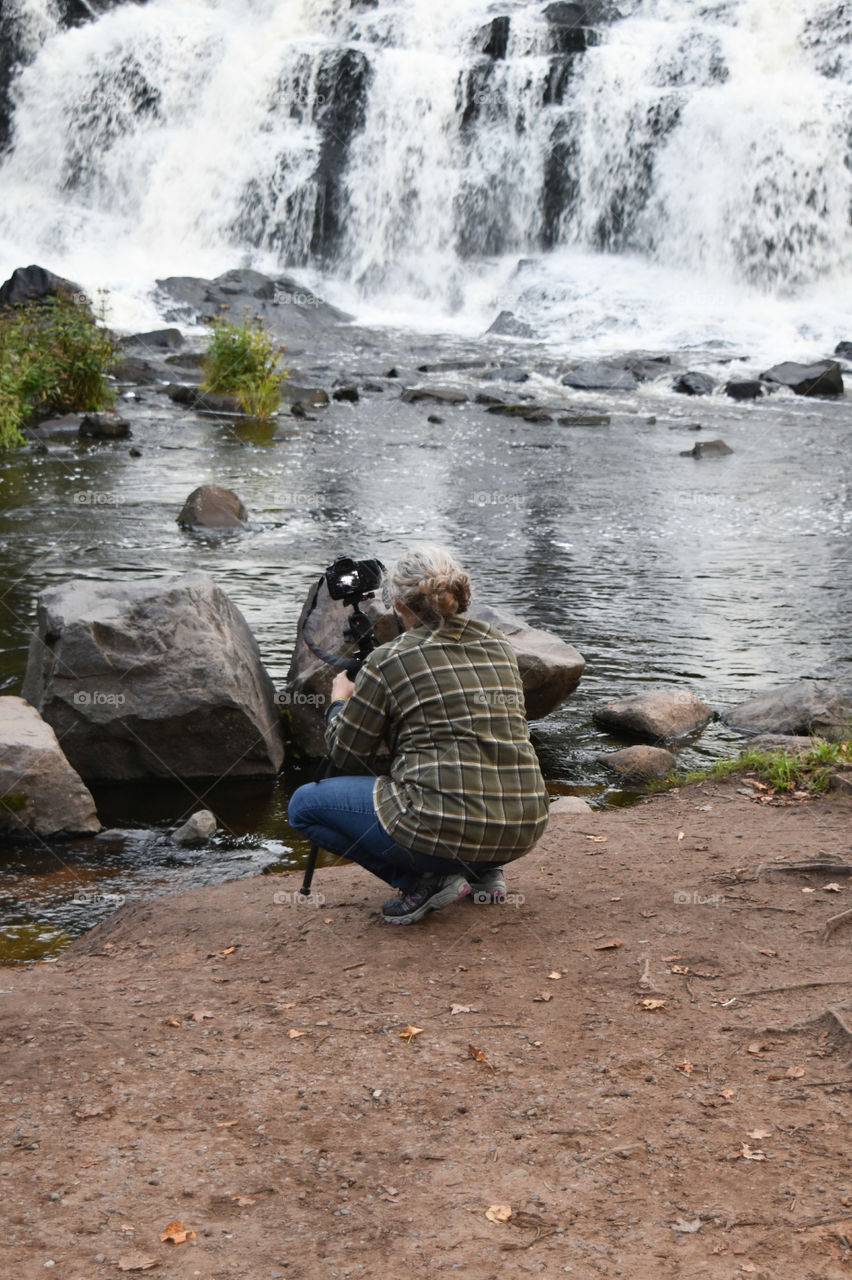 Woman taking a photo of a waterfall
