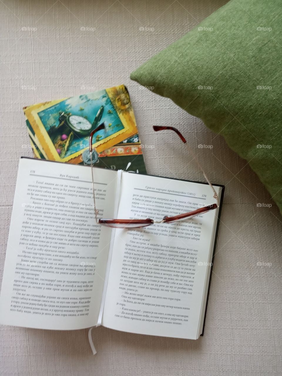 Arrangement of green pillow, books and glasses.