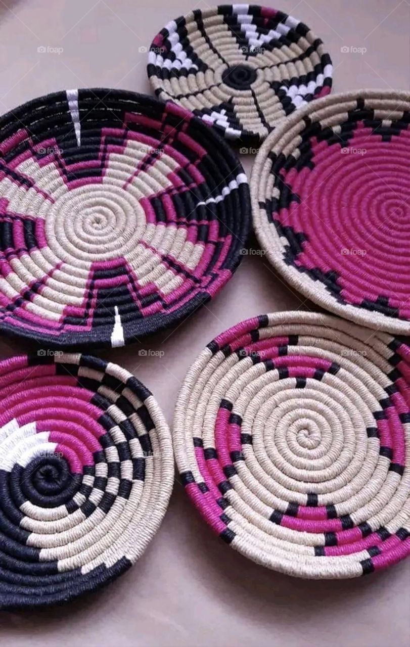 The image shows a group of hand -made dishes of wicker, decorated with colored embroideries with beautiful floral shapes, and is elegantly displayed in a warm corner that combines heritage and beauty, which gives the place an artistic spirit and attr