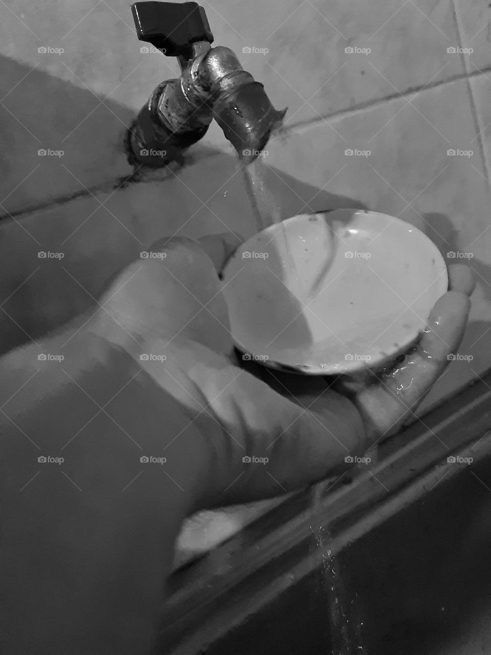 A hand washing a mini plate under the water tap in the form of fine art style