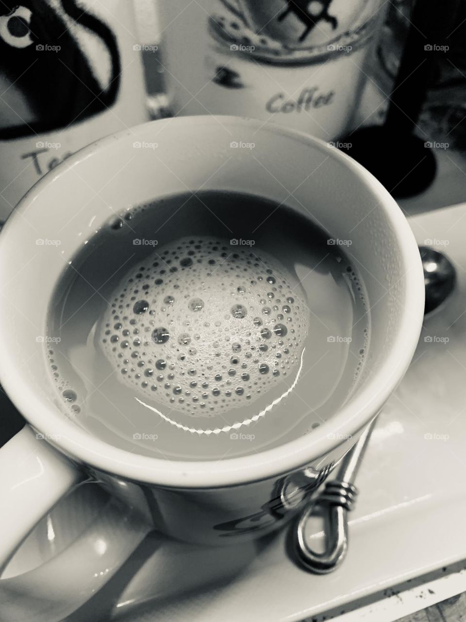 A morning cup of coffee to get the day started right. A home brewed cup of Joe, bubbles, and a silver spoon.