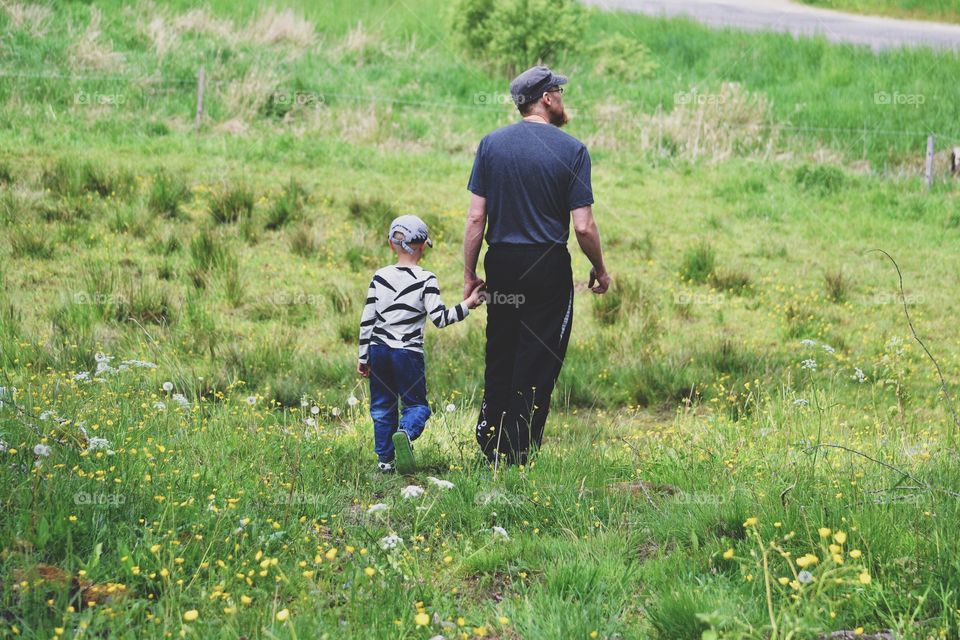 Father and son holding hands while walking in the nature