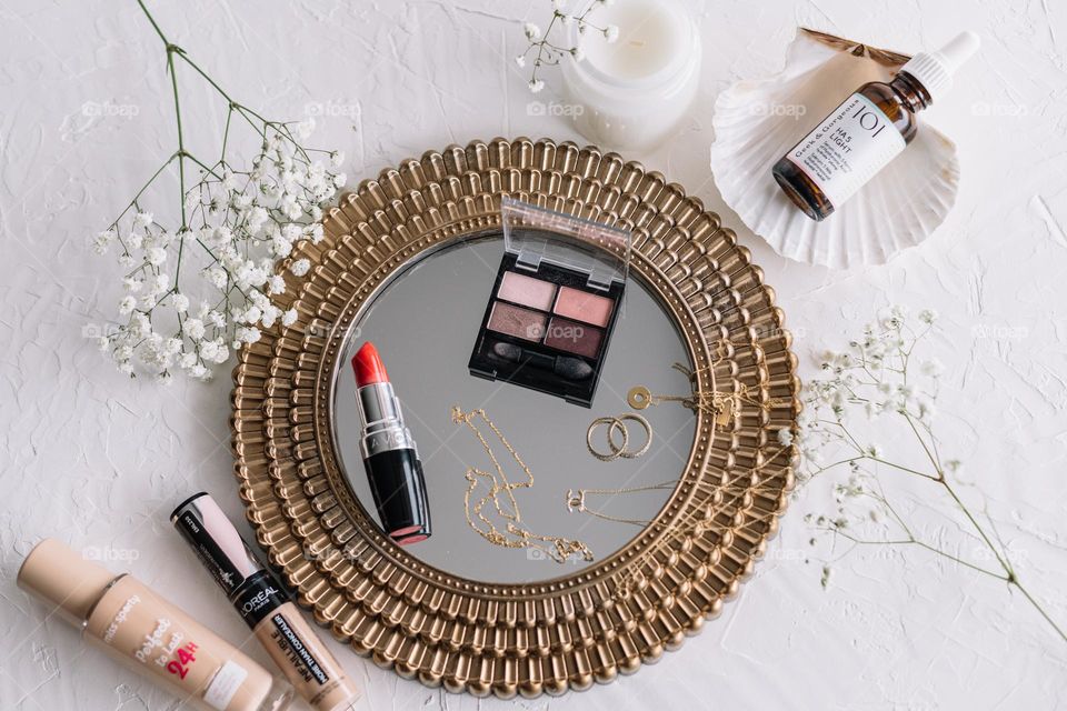 Gold jewellery, Red lipstick, eyeshadow makeup palette, foundation, serum.