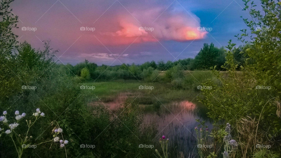 Beautiful clouds at sunset with reflections in the water of a creek. Near Targu Mures, Transylvania in Romania.