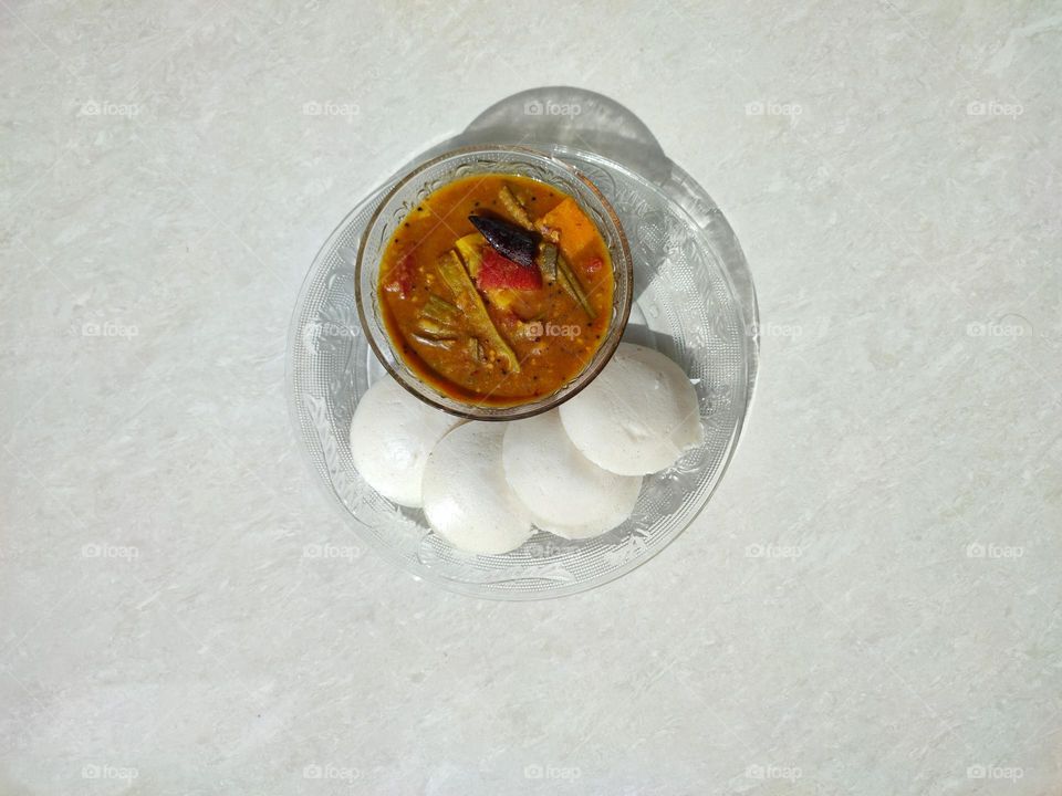 Idli and sambar, sambar a vegetable curry medium spicy, Idli is a pure white colour fluffy steamed batter consisting of fermented black lentils (de-husked) and rice