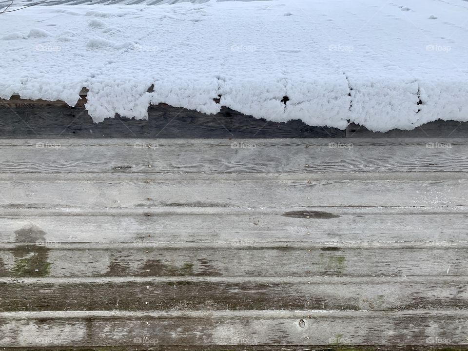 Snow and ice melting off of a metal roof of a rustic wooden structure 