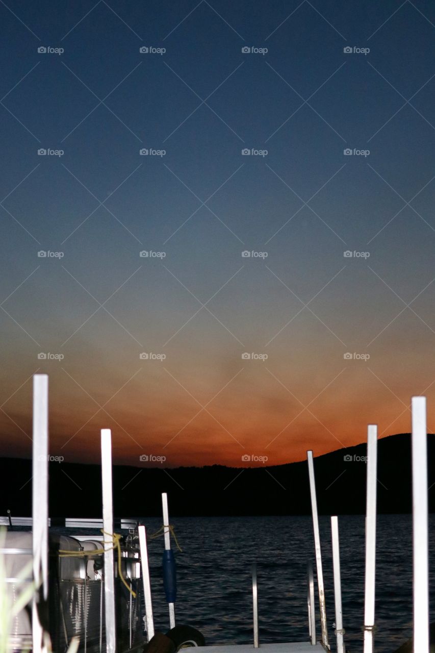 Sunset on the lake boat tied to dock backlit image 