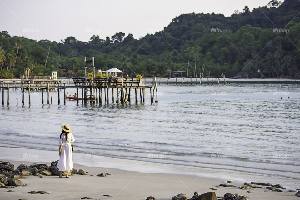 Asian woman on the beach the background sea and a wooden bridge at Koh Kood, Trat in Thailand.