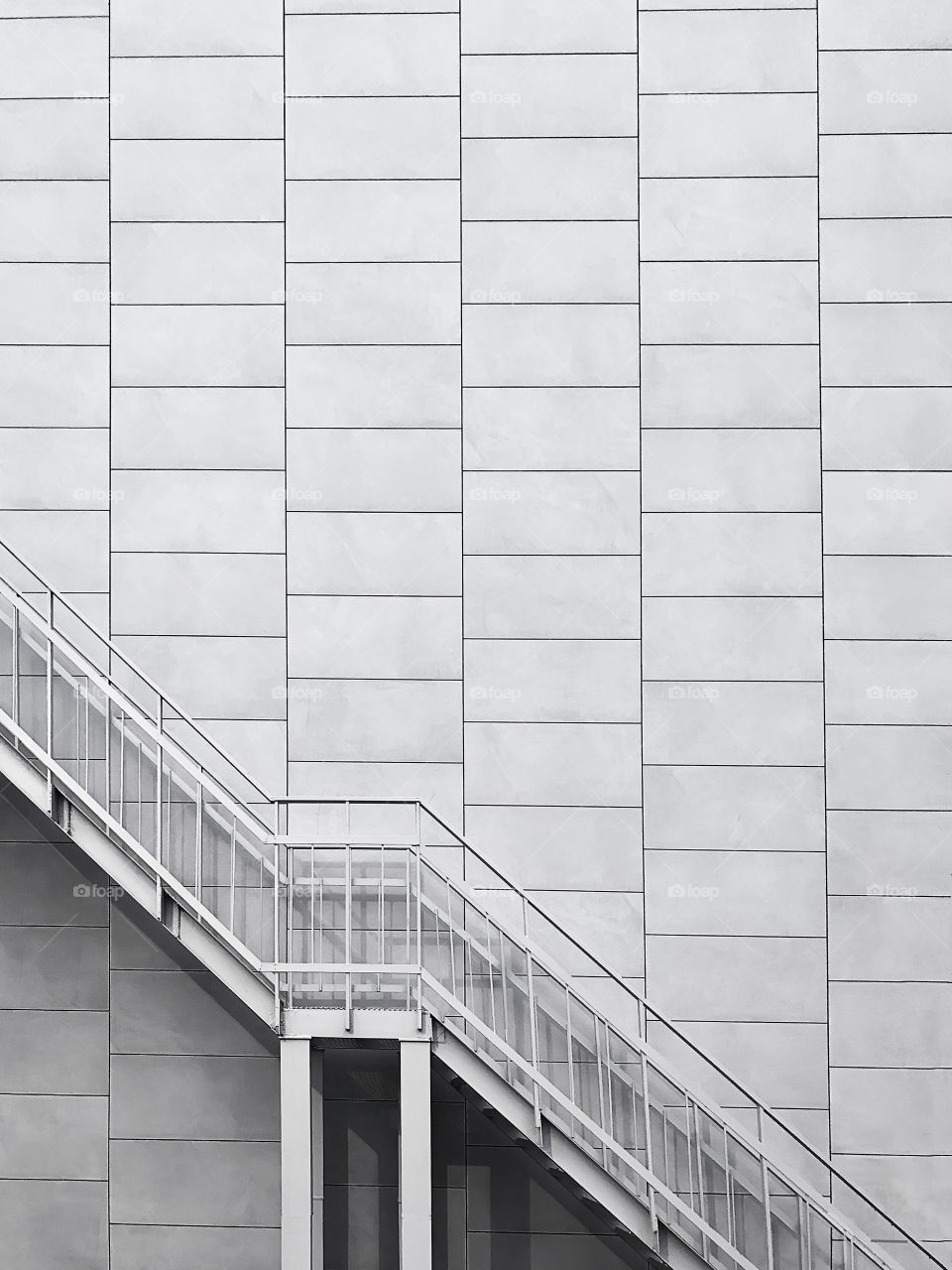 Minimalistic architectural fragment of metal stairs on bright wall background black and white 