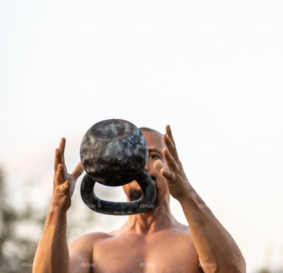 Selective focus to the throwing kettlebell by the man workout at the outdoor. Healthy lifestyle.