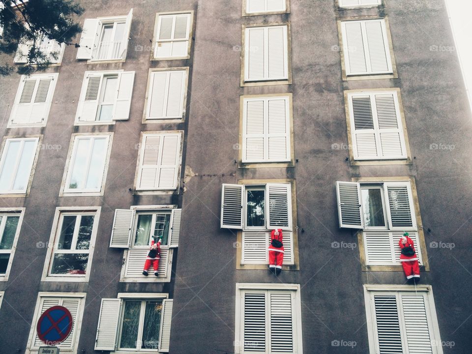 3 decorative figures of Santa Clauses outside the window of the house.