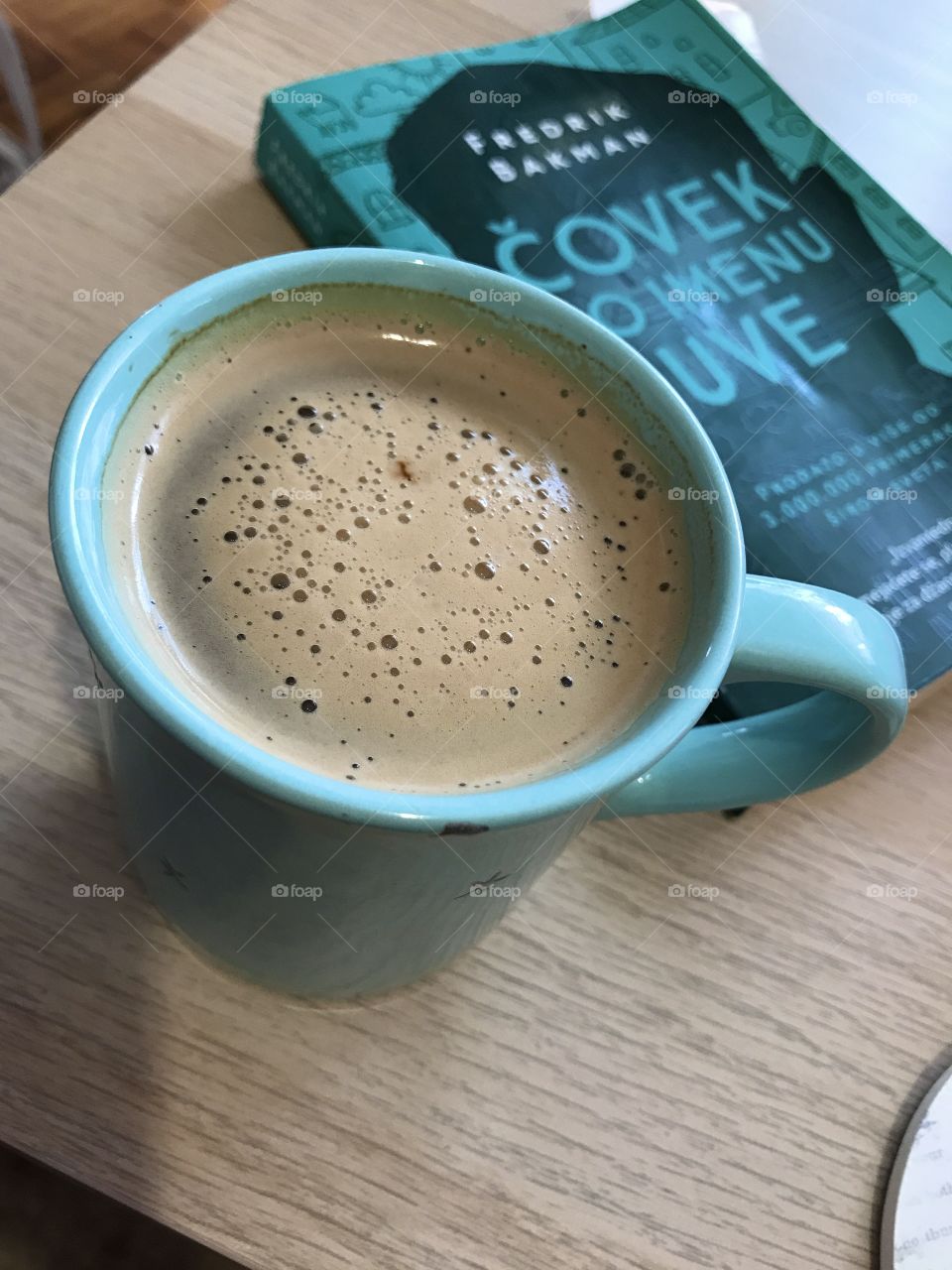 Big mint green cup of ness instant coffee and big green book ,,A men called Ove’’ in serbian language.
