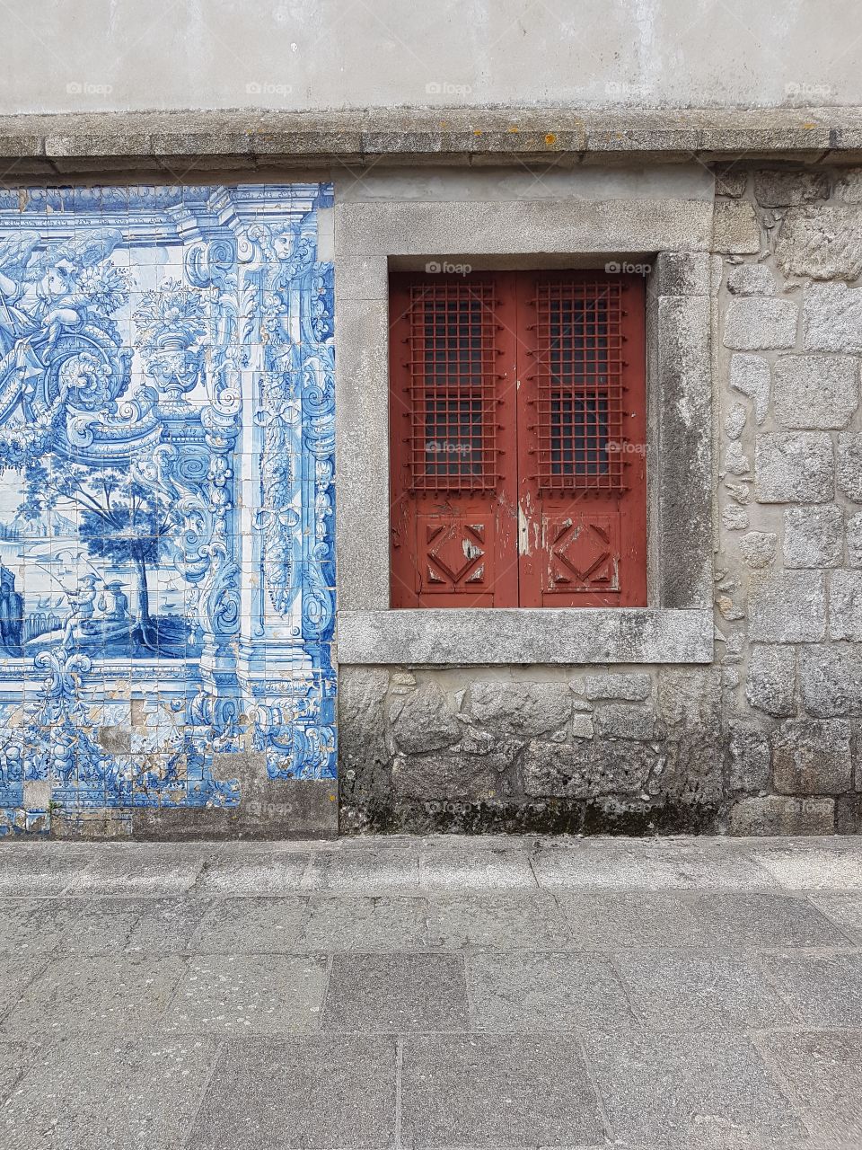 Red and closed window besides a blue tiles wall.