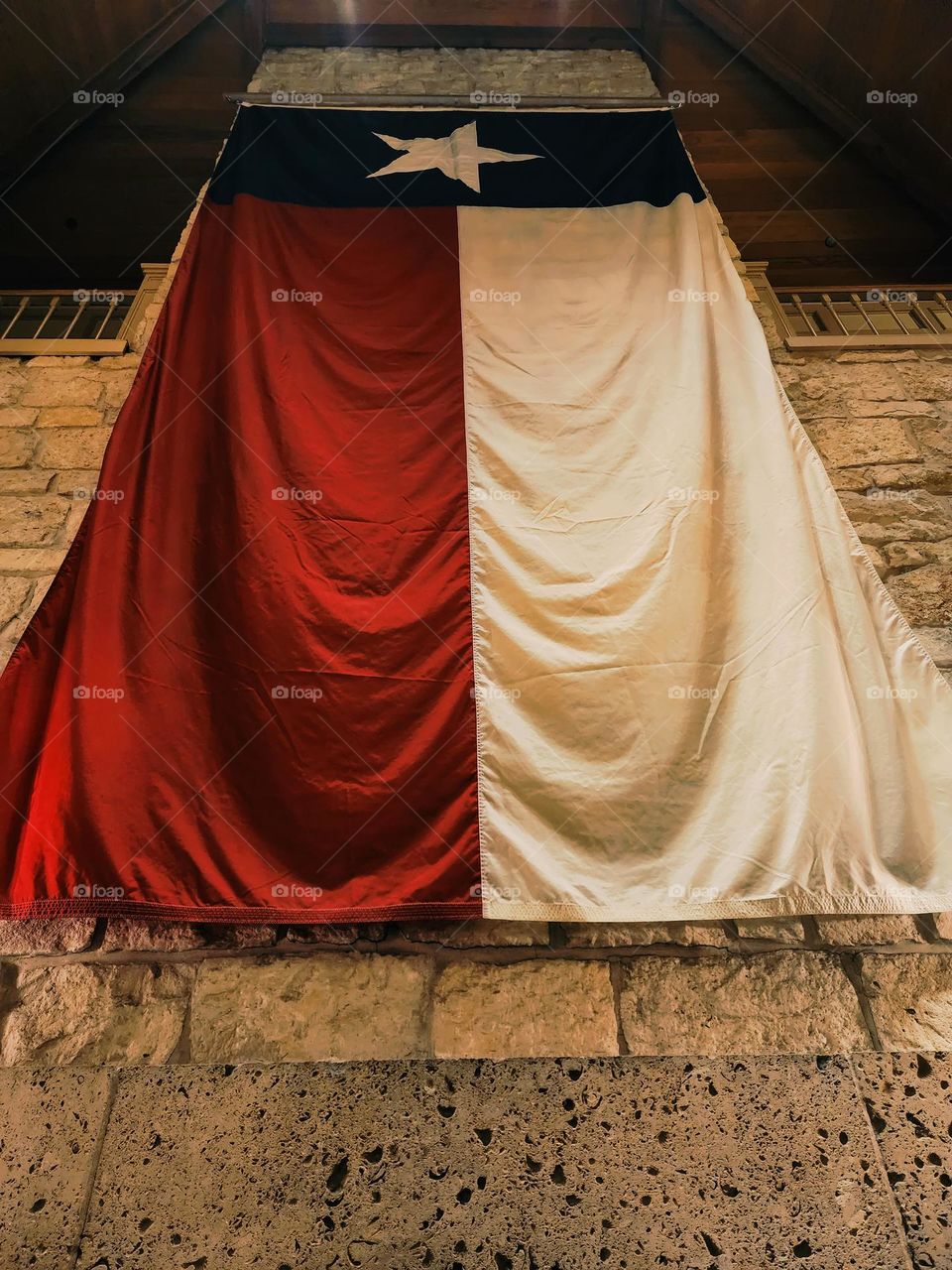 A large Texas state flag highlights a wall of stone and wood and features rich, warm colors
