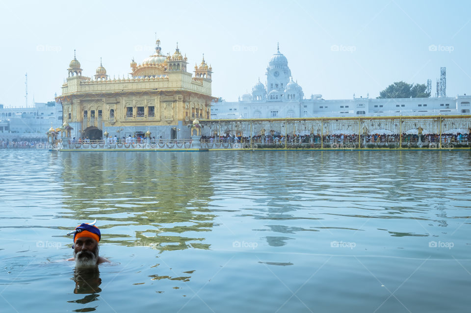 Unidentifiable Punjabi Sikh pilgrim devotee "Nihang Warrior" taking bath and prayer in pond and meditating in front of Golden Temple ("Harmandir Sahib Darbar Gurudwara") Amritsar, Punjab, India, Asia.