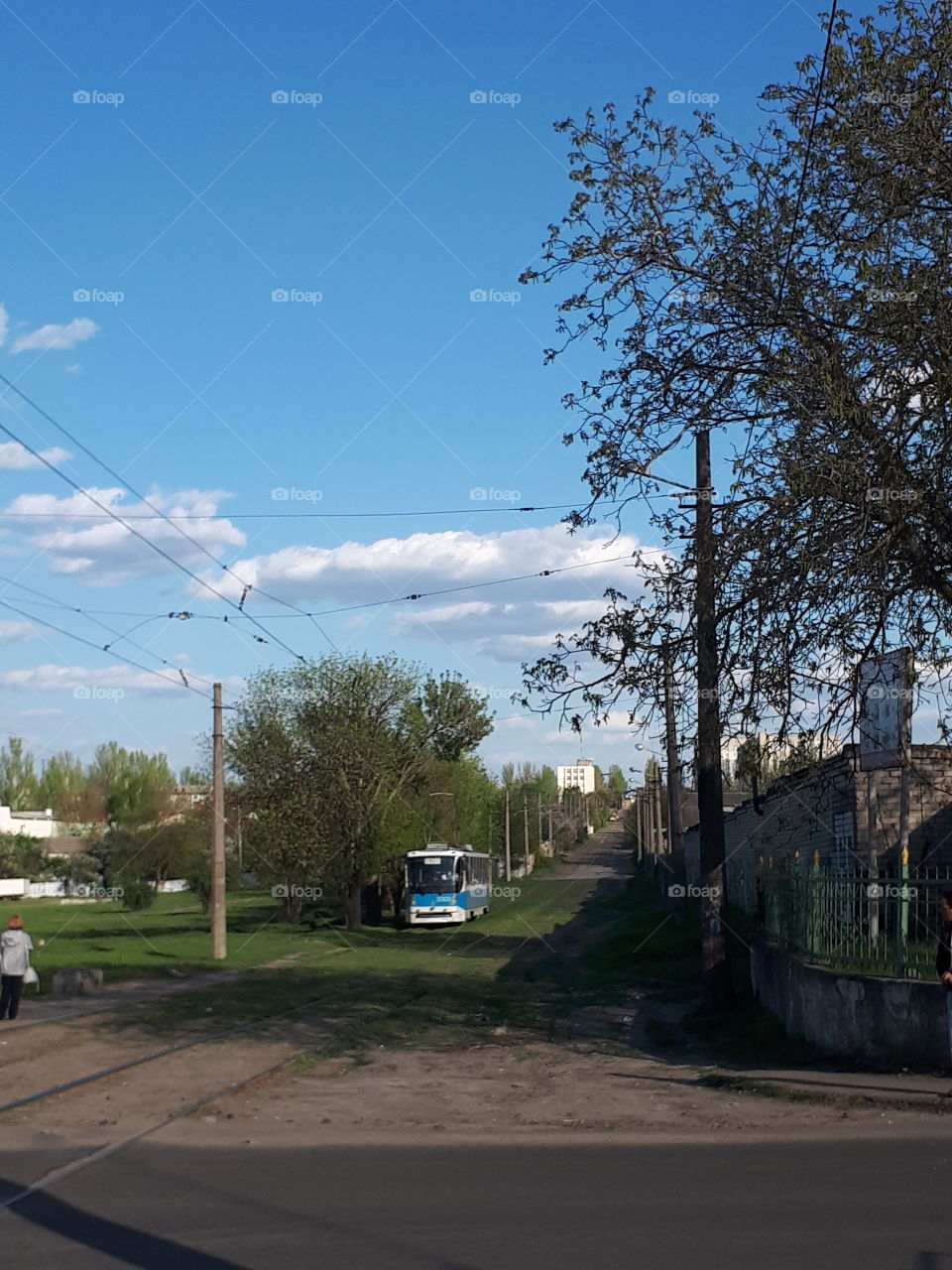 The blue tram is riding down the street