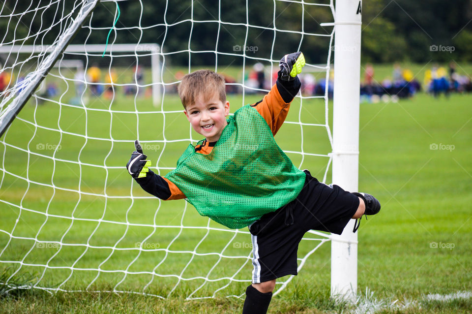 Young boy smiling and playing goalie during soccer game