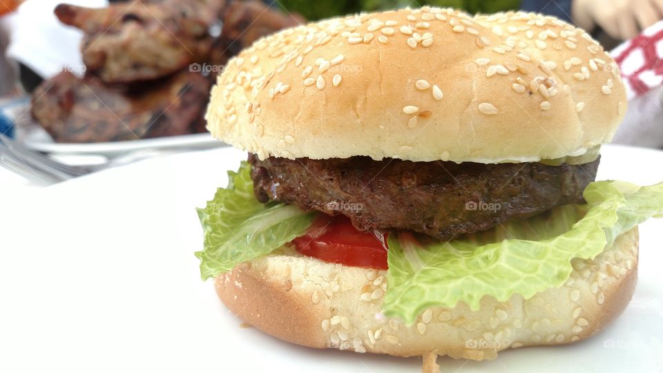 Close up of hamburger with meats behind.