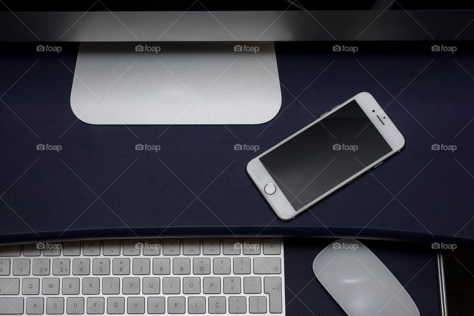 Top view looking down a monitor to phone, keyboard & mouse on desk