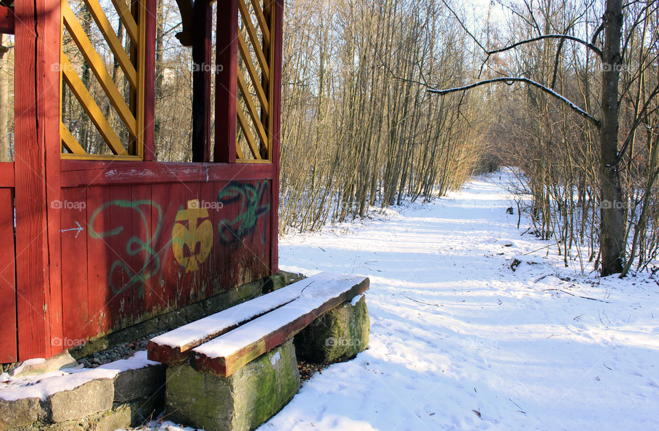 wooden Pavillon and a bench on a forest footpath in winter