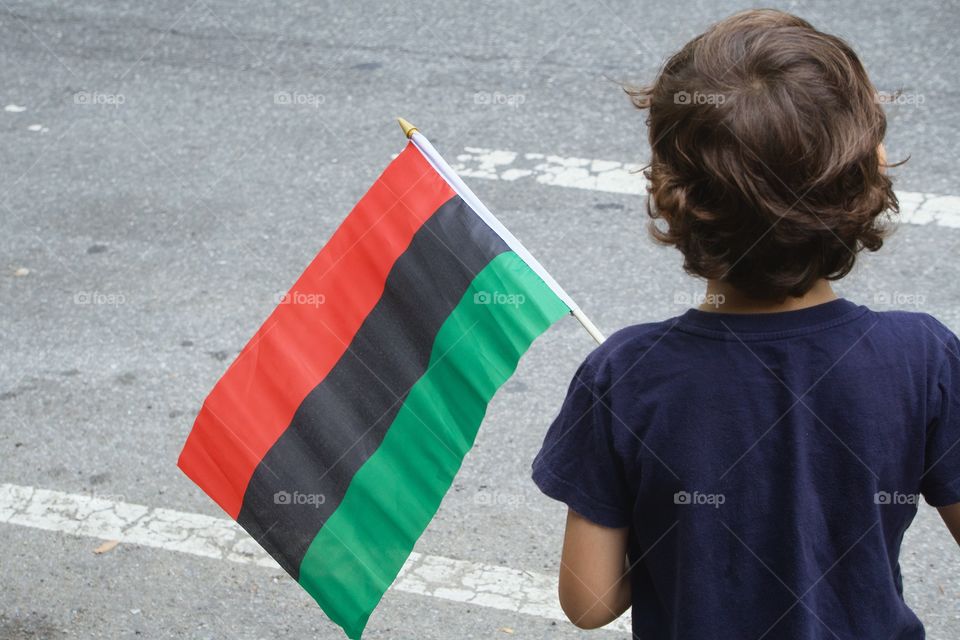 Boy with flag at the African American Parade in Harlem , New York City