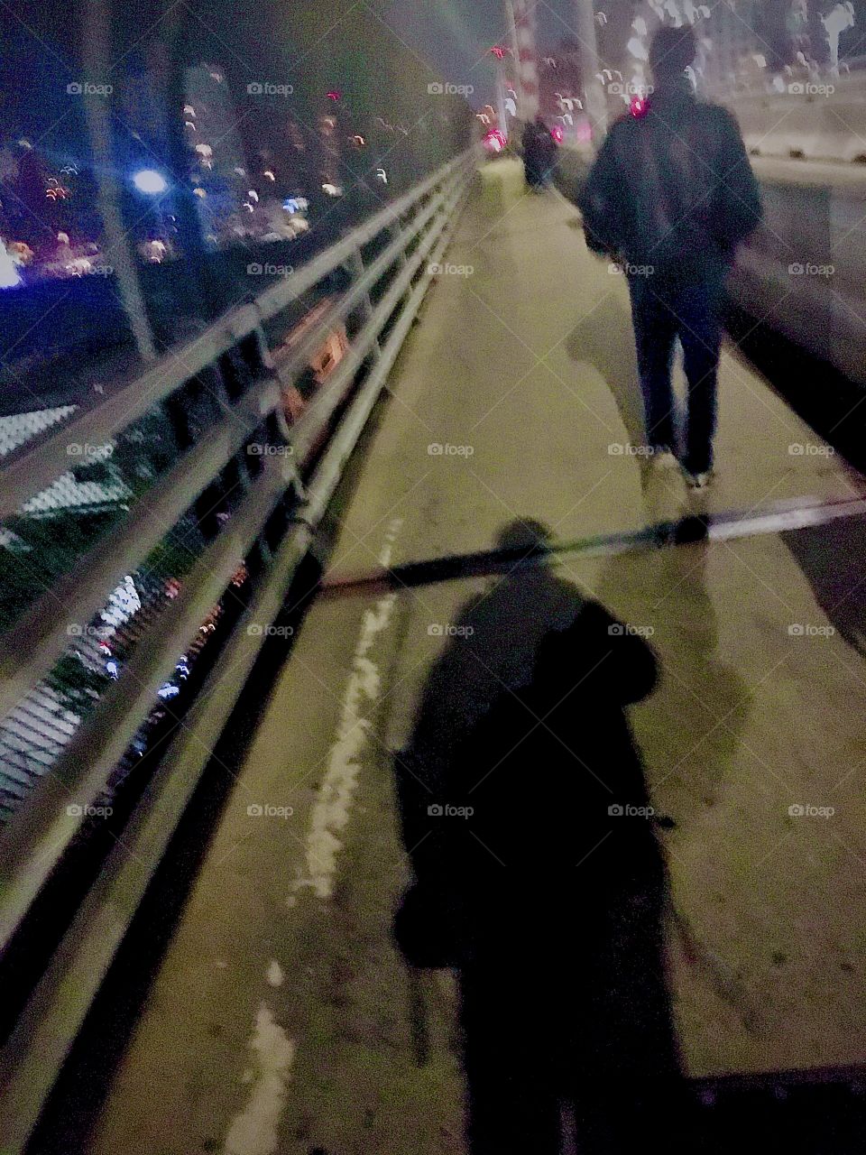 A pedestrian walks away and my shadow seems to follow him as I’m taking this picture in October 2020 on the pedestrian lane of the Pulaski Bridge that connects Greenpoint, Brooklyn and Long Island City, Queens, NY. Hypnotic Productions