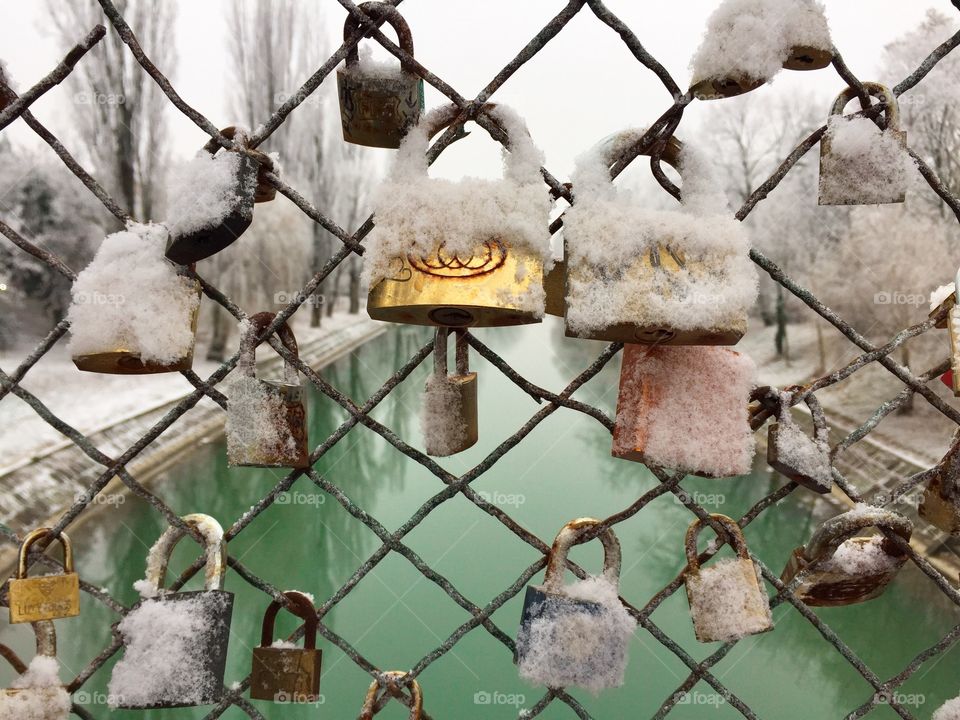 Padlocks covered in snow on the bridge