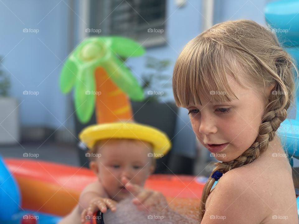 small children swim in the pool on a hot summer day