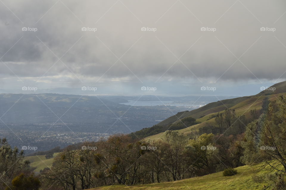 Fog descends over a hill overlooking a populated valley