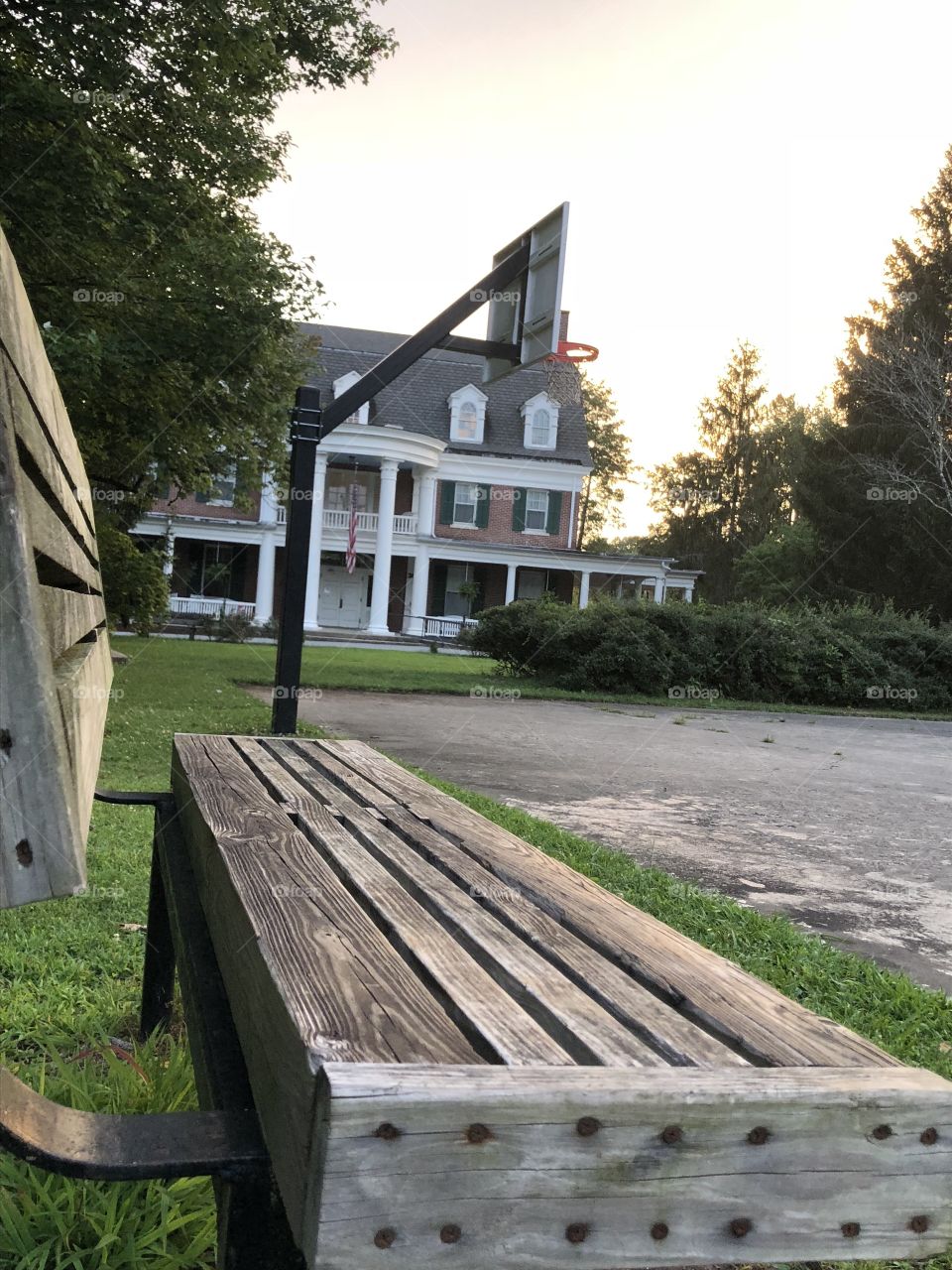 The rectangular shapes of the park bench lead the viewer’s eye to a very special basketball goal where I hit my first left handed layup as a kid. Post-sunset light trickles through the trees and illuminate the house and basketball court. 