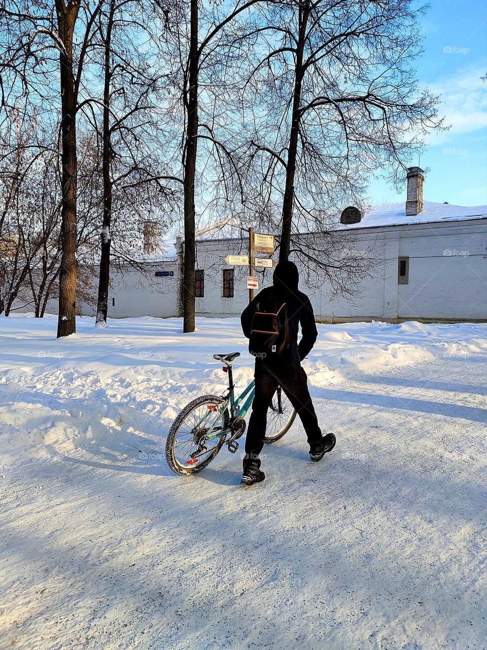 Life in motion.  A man walks along a snowy path and rolls a bicycle.  Winter cycling.  Sports and recreation