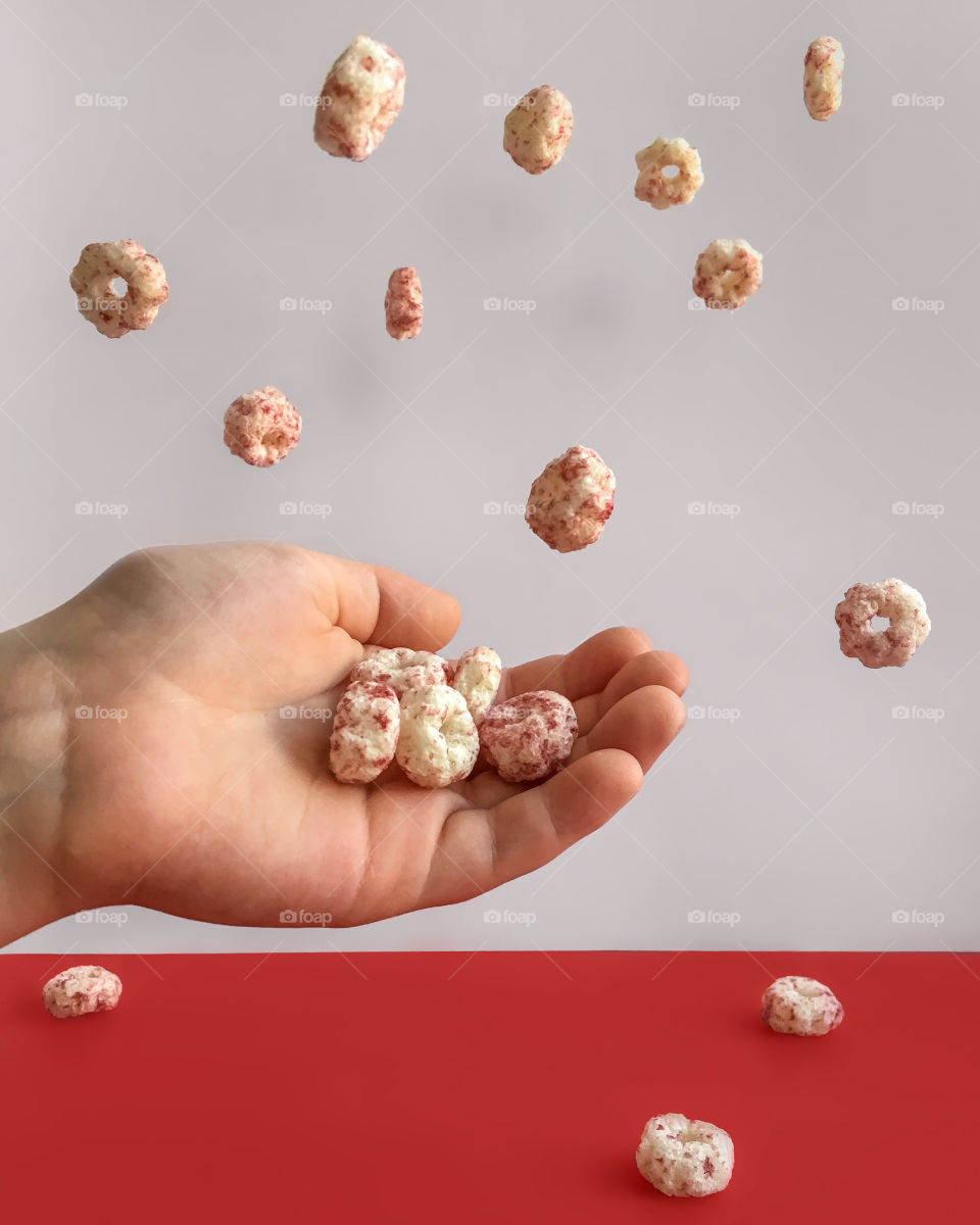 Levitation puffs on grey and red background, child’s hand