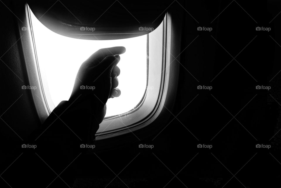 Hand by aeroplane window silhouette. 