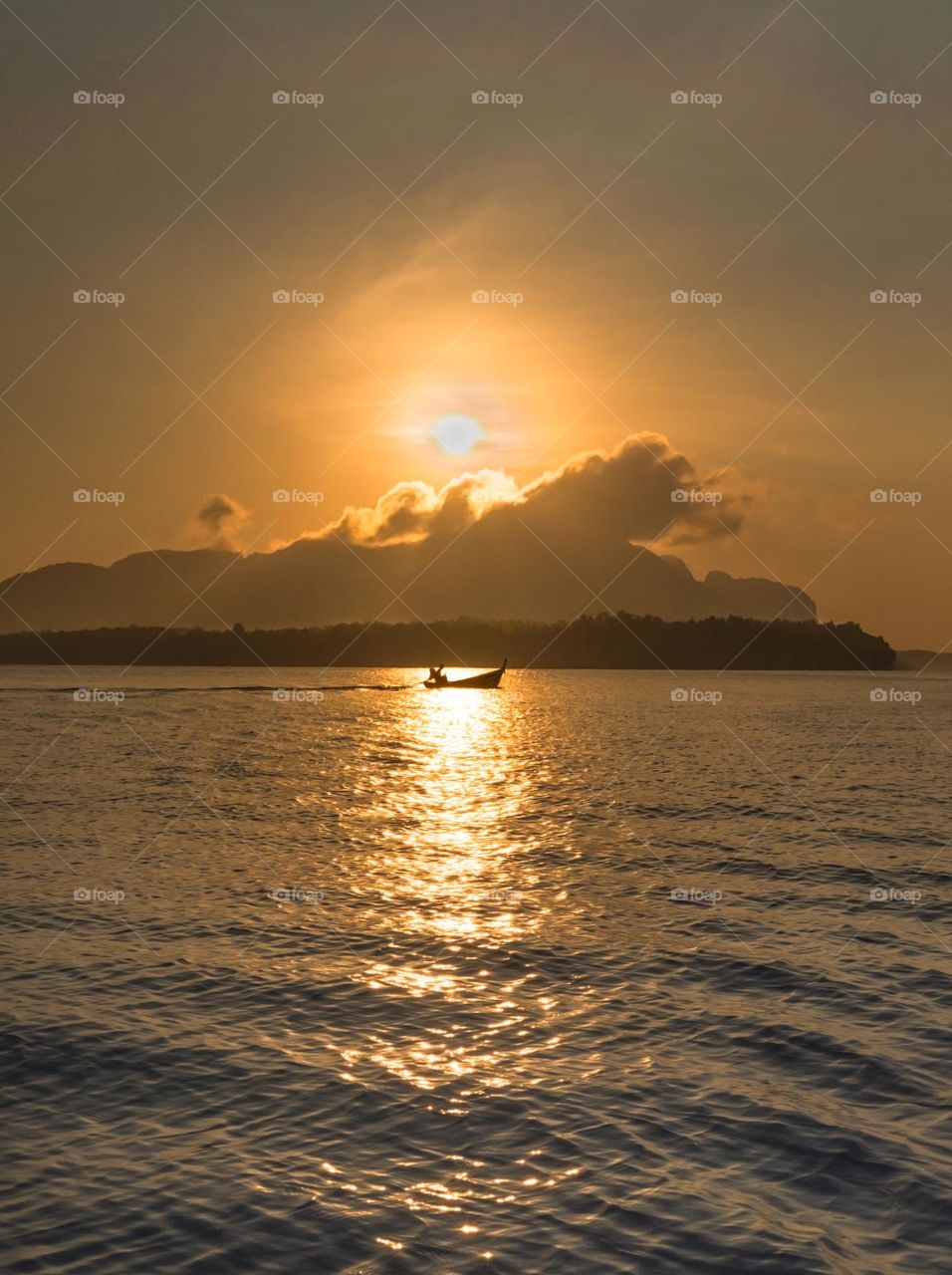 Sunrise above silhouette of boat in sea