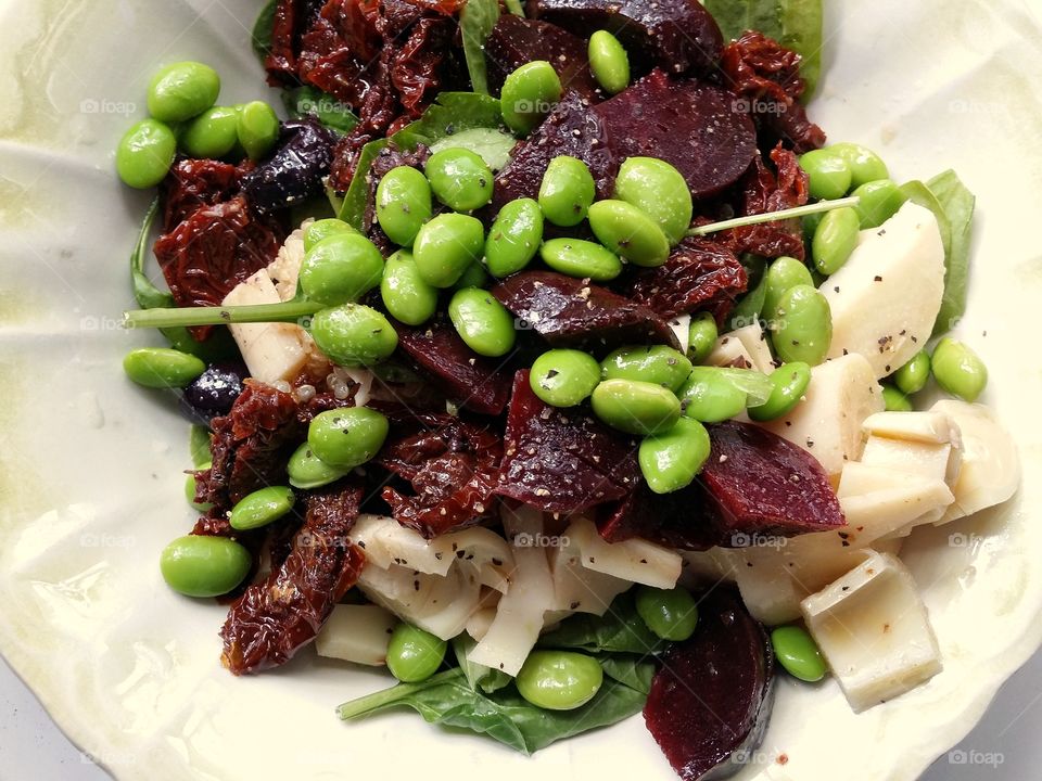 A colorful edamame beet sun dried tomato hearts of Palm and spinach salad